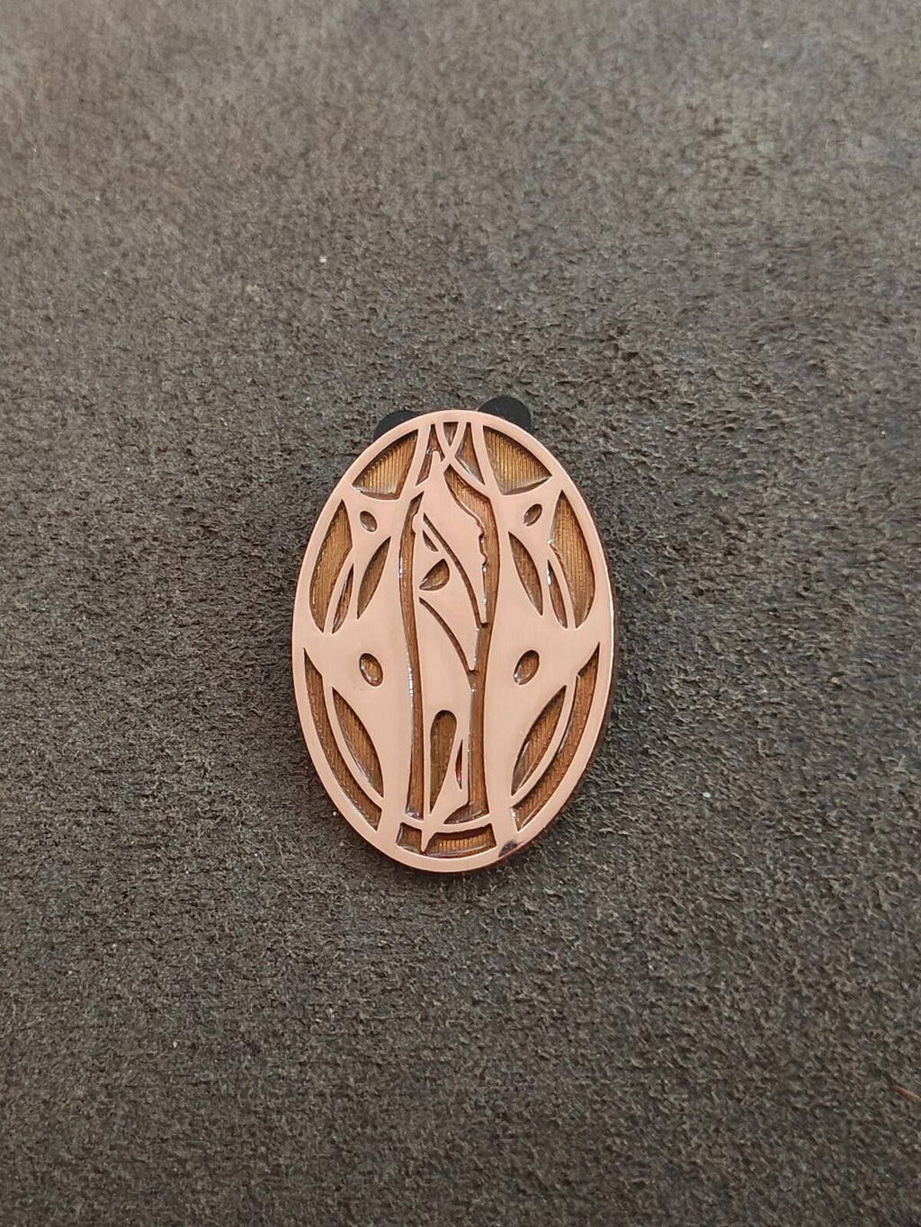 Apricot oval pin featuring leaf-and-vine cutouts with a gold-tone border
