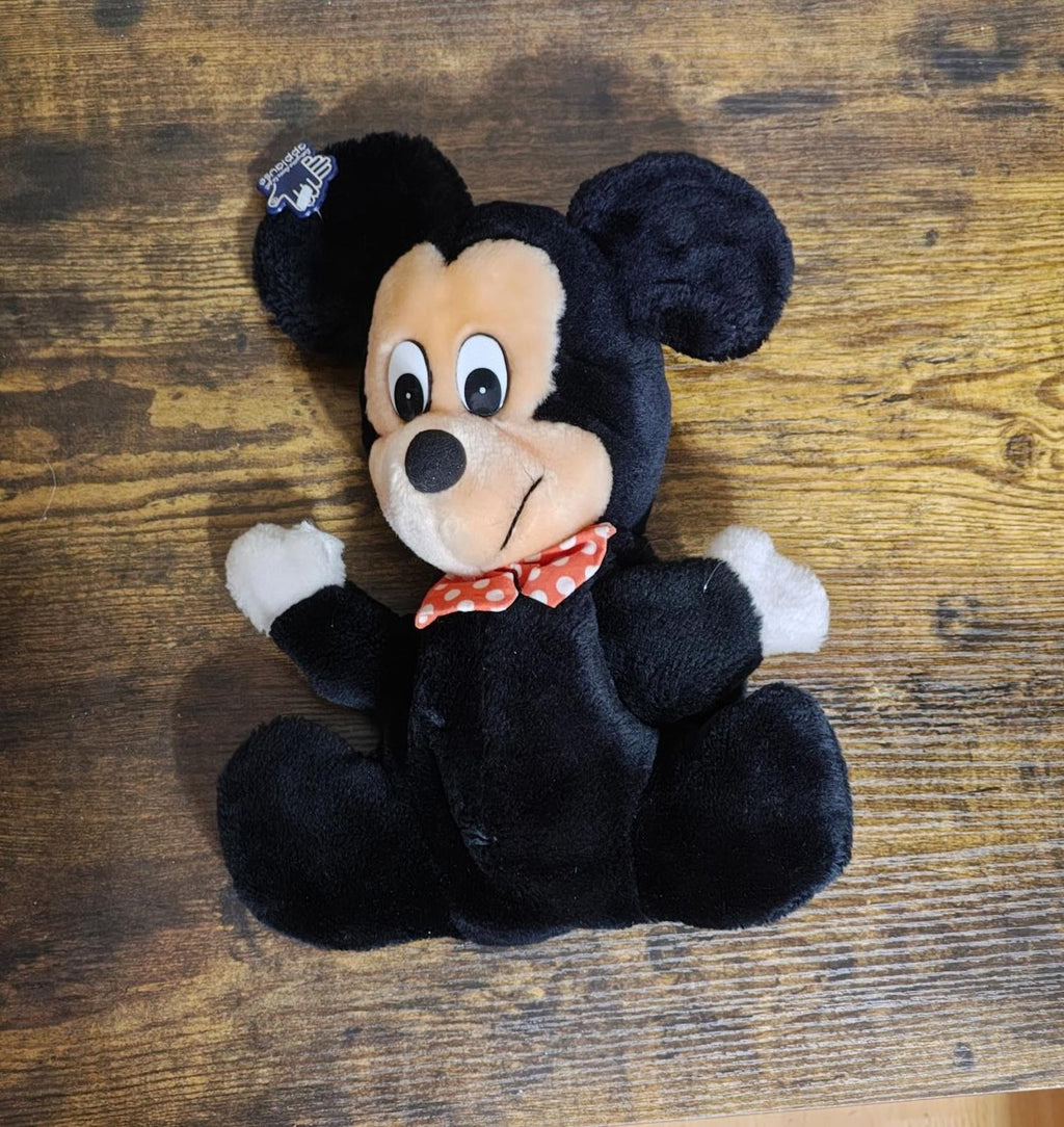 Black Mickey Mouse plush hand puppet lying on a table with red bow tie