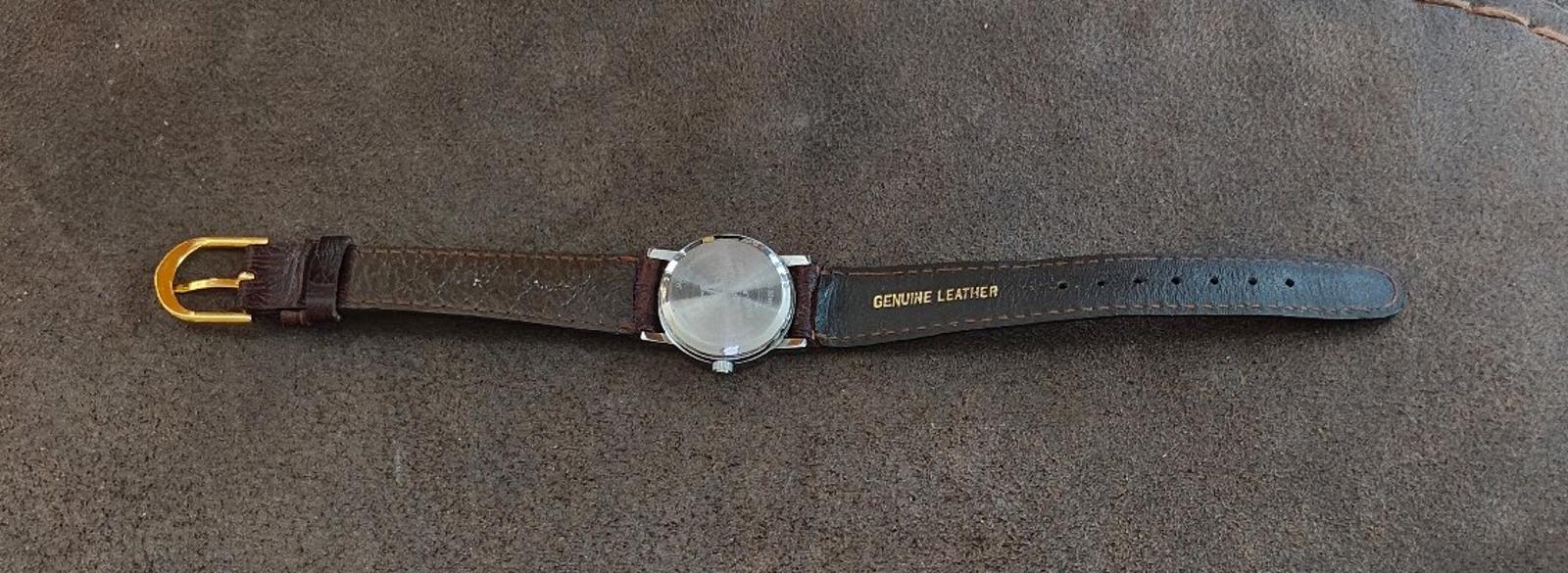 Brown leather wristwatch laid flat with round silver case and dark buckle