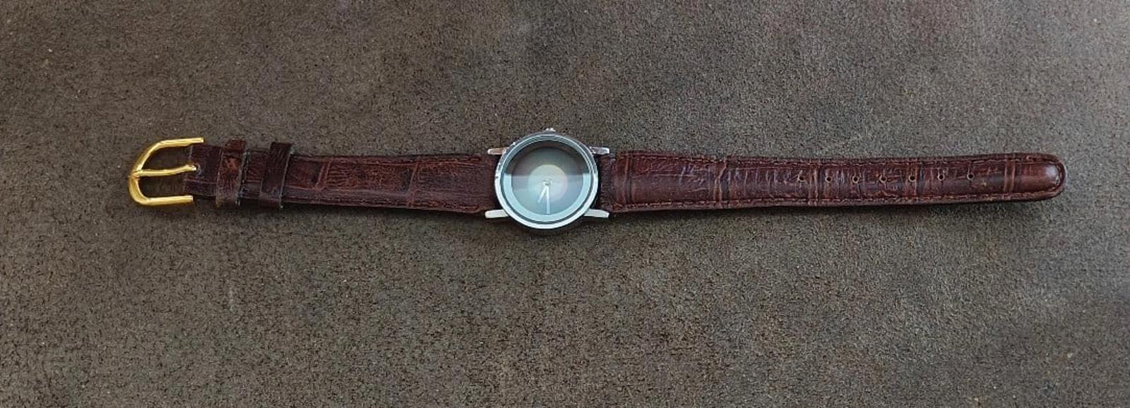 Brown leather wristwatch laid flat with small round case and gold-tone buckle