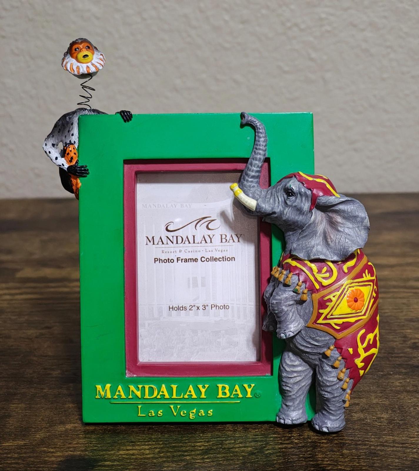 Green souvenir photo frame with elephant figurine and monkey perched on top