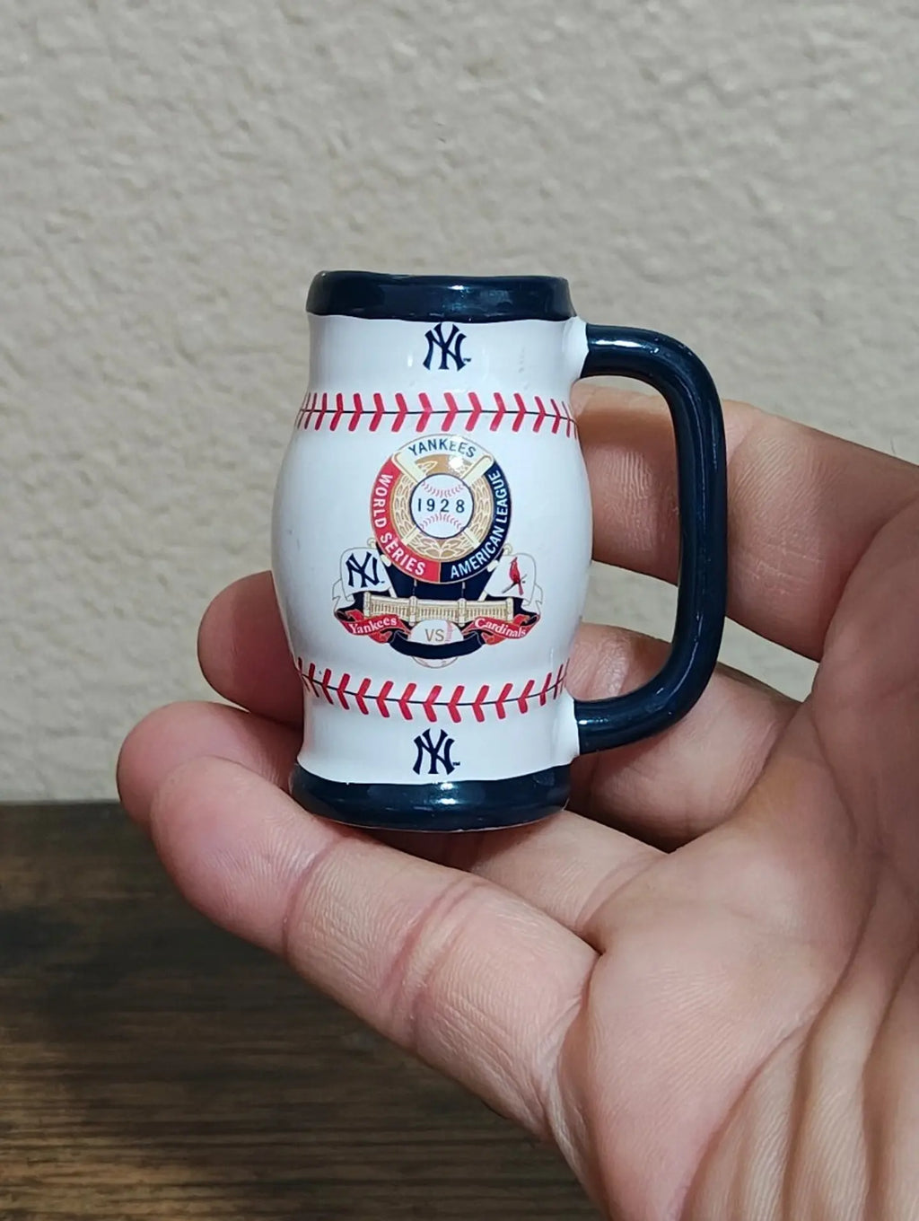 Miniature ceramic mug, white with navy handle and base; red baseball stitch and Yankees logos