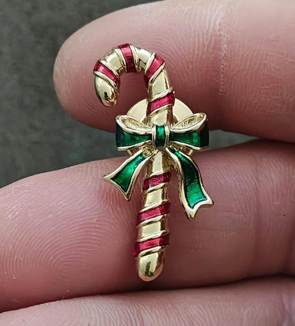 Candy cane enamel pin with red-and-white striped cane and green bow detail