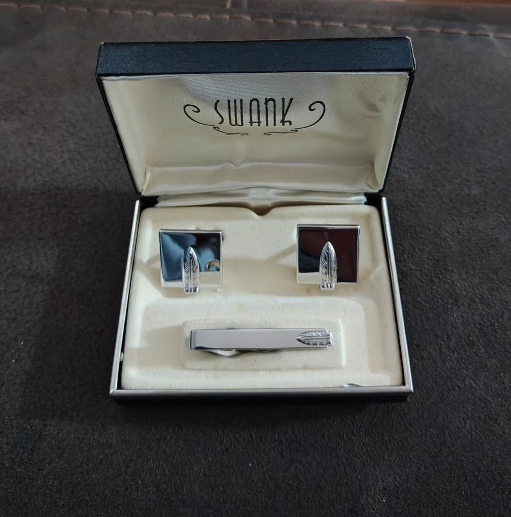 Silver-tone feather motif cufflinks and tie bar set in open box on fabric