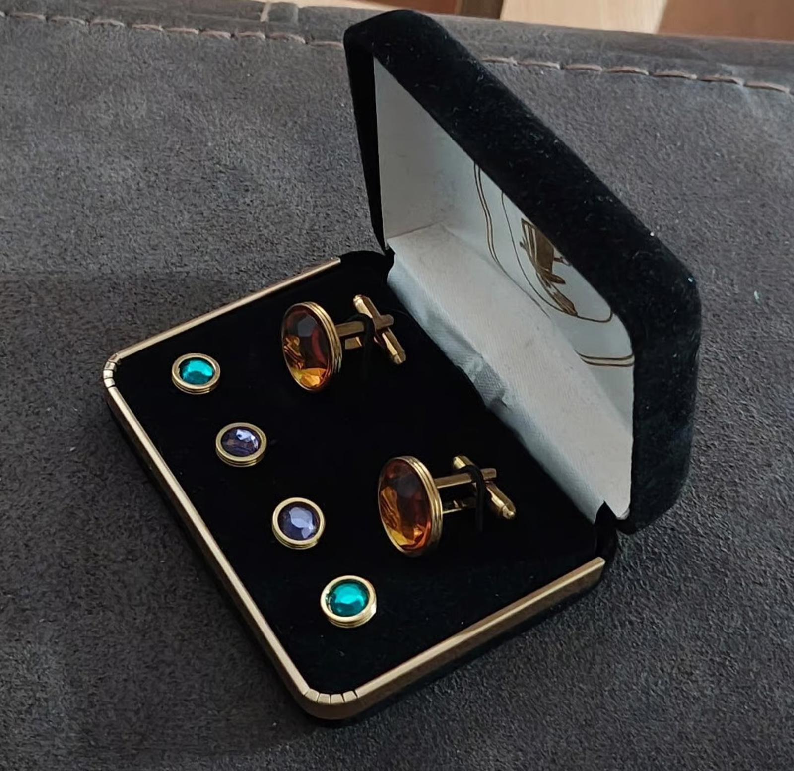 Jewelry set angled in open box: round gold-tone cufflinks and blue/teal shirt studs