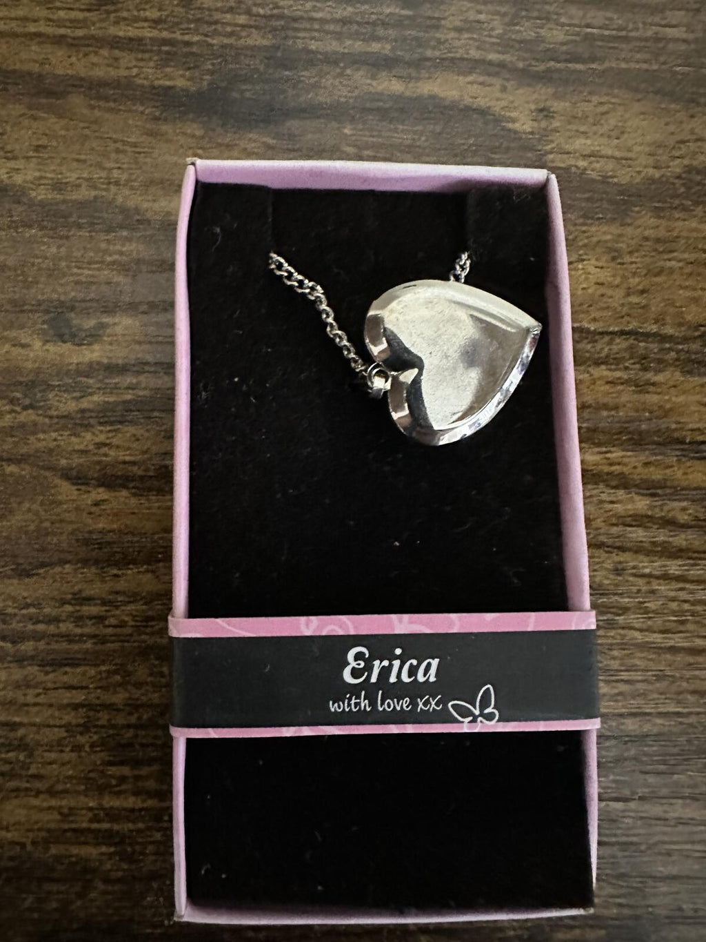 Silver-tone heart locket pendant with chain in pink gift box, showing back side