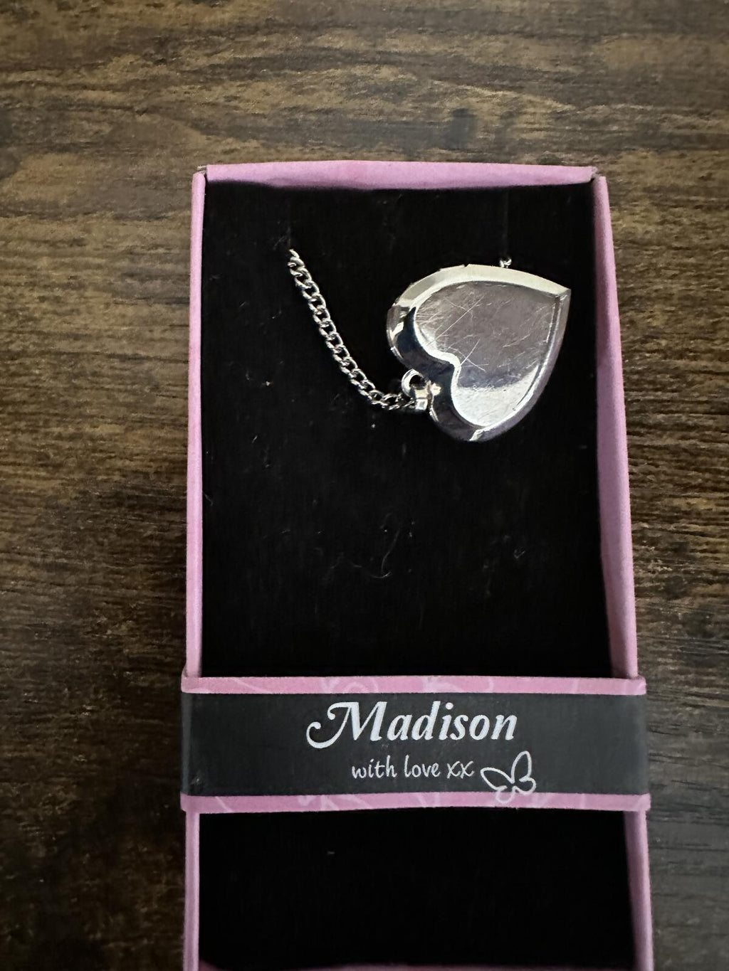 Silver-tone heart locket necklace in box showing heart back detail on chain