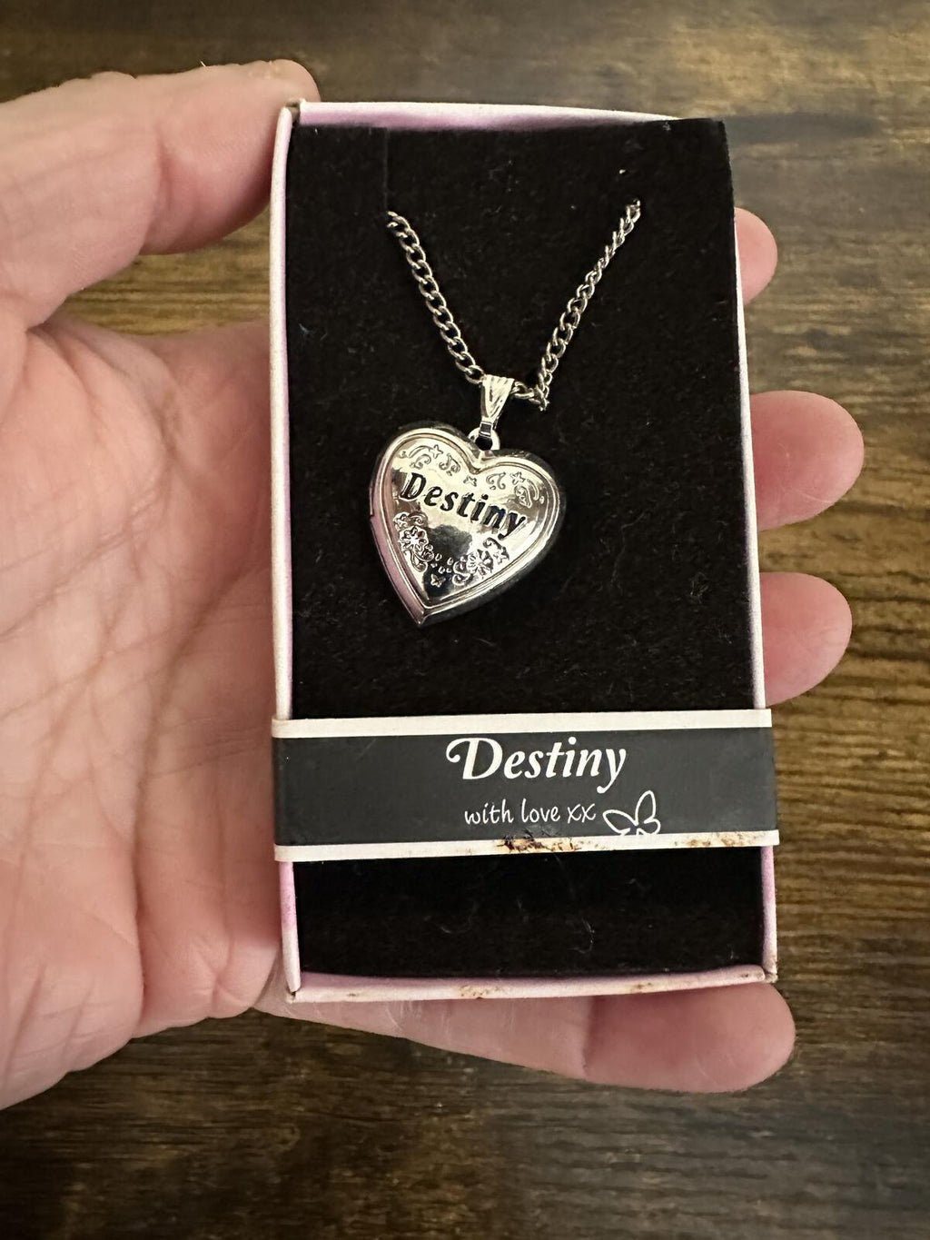 Silver-tone Destiny heart locket necklace in hand, “Destiny” engraved on heart