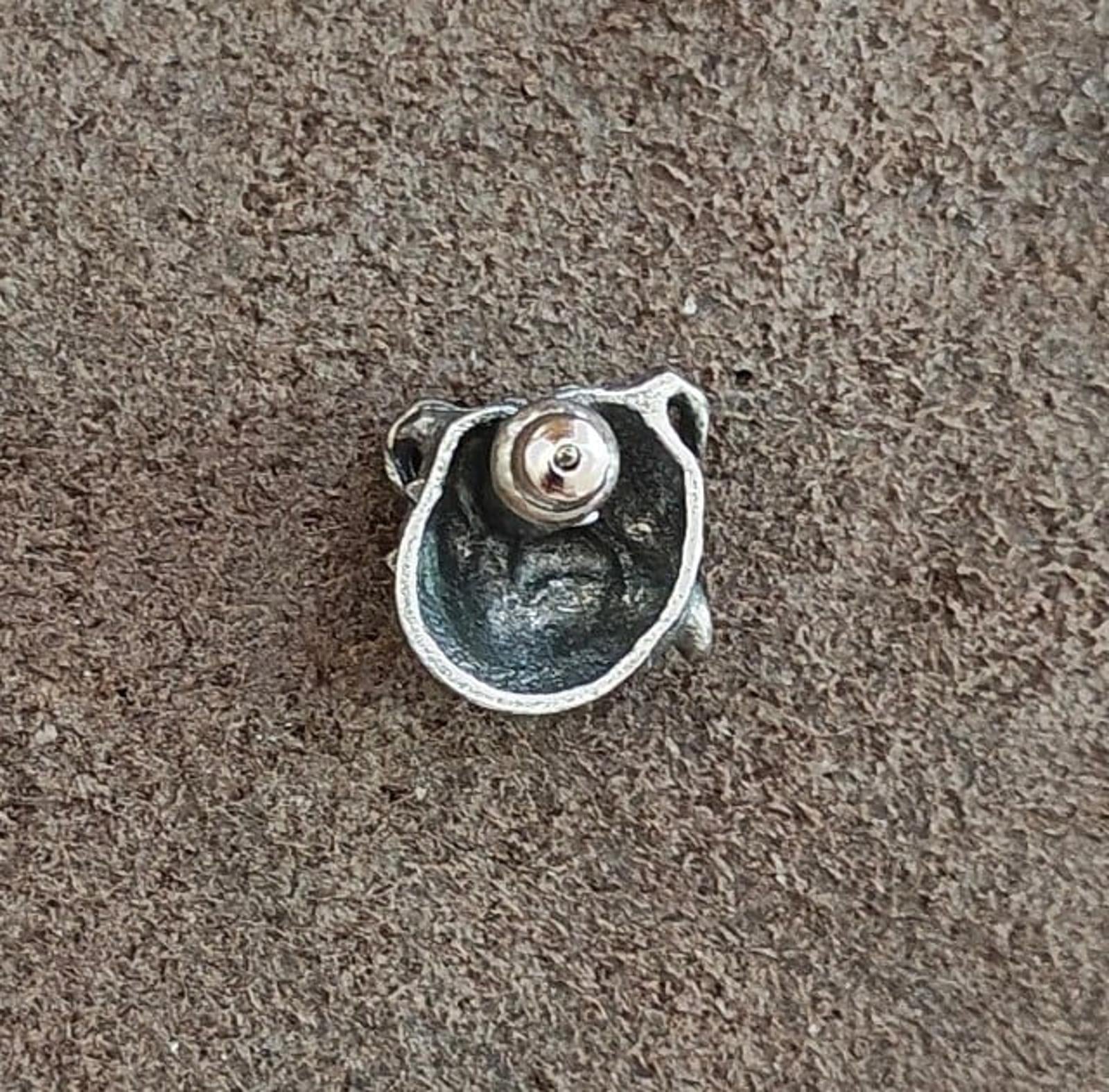 Back of a silver-tone bulldog head pin showing a round clasp