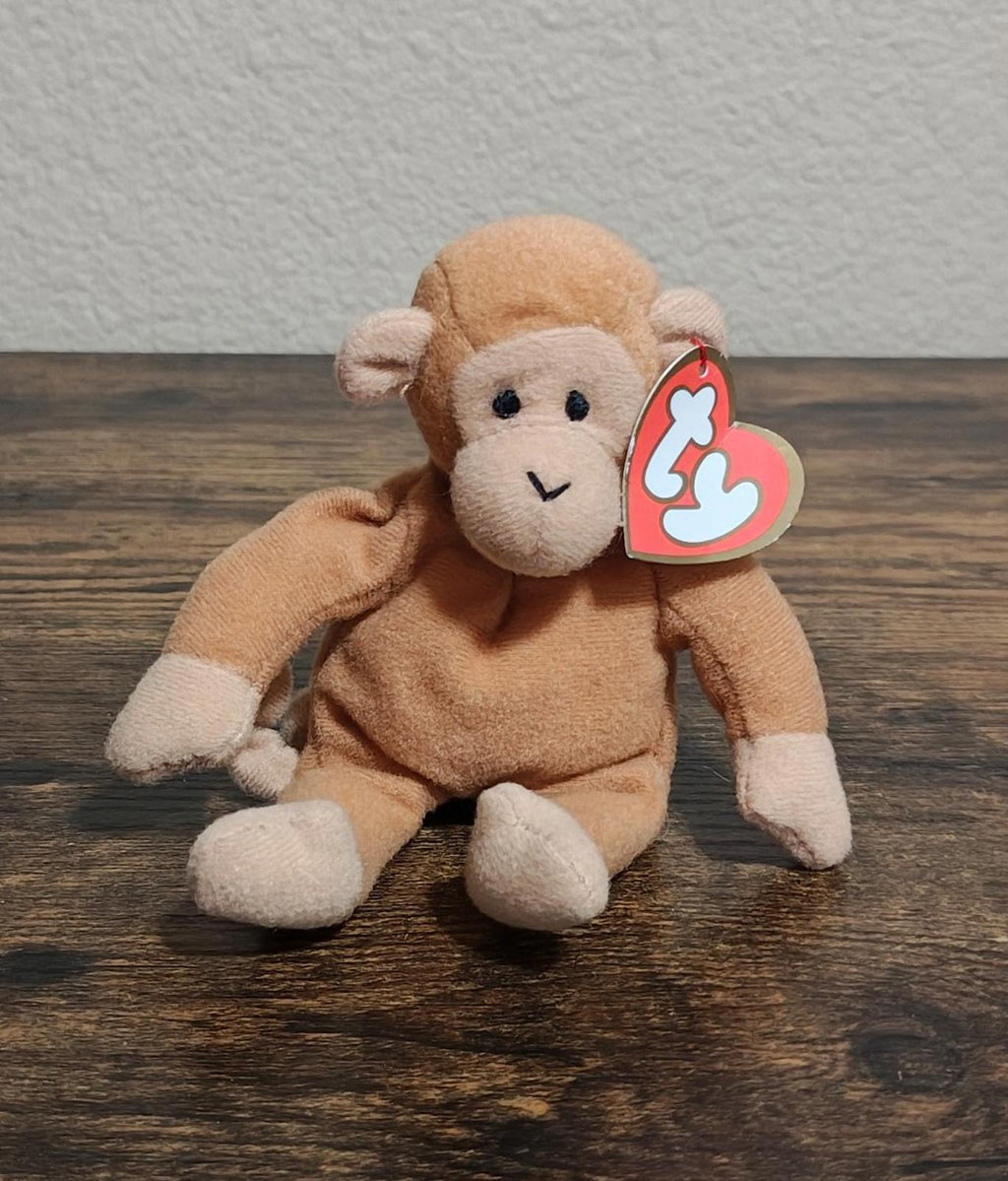 Brown Ty Beanie Babies plush monkey on wood surface with heart tag visible