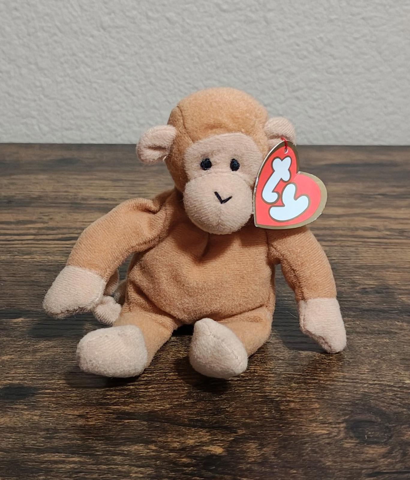 Brown Ty Beanie Babies plush monkey on wood surface with heart tag visible