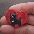 Red glitter heart pin with black scottie dog and pink tongue, held in hand