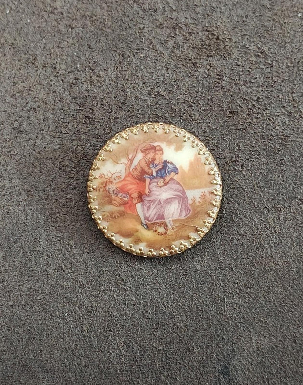 Gold beaded-edge oval cameo brooch featuring a couple in a romantic painted scene