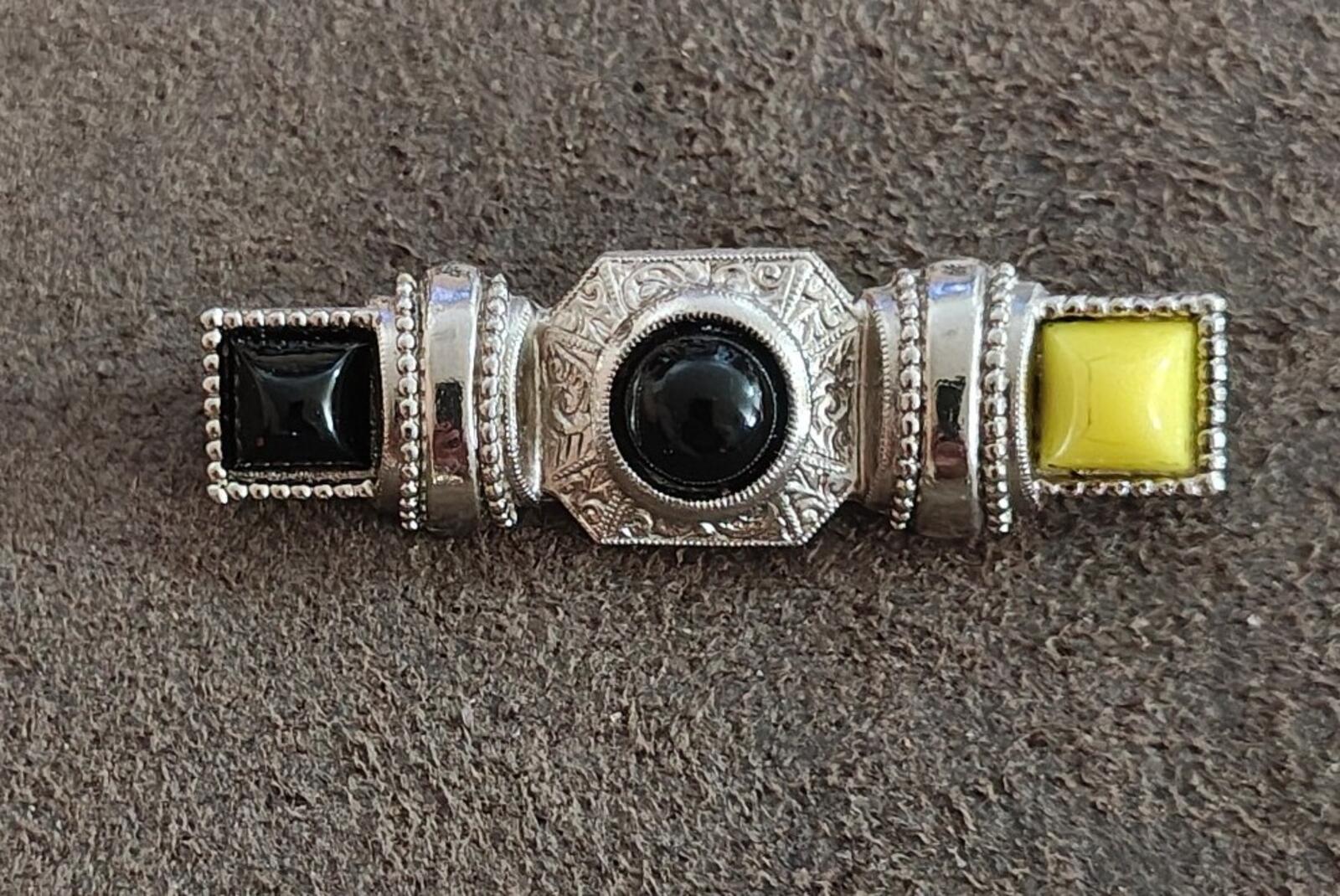 Silver-tone bar pin brooch with round dark cabochon center, black square, and yellow square ends