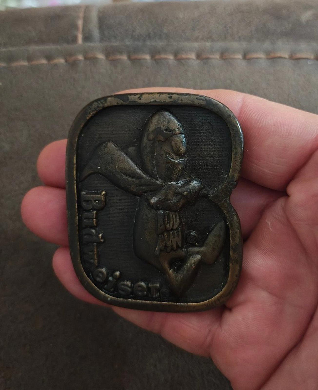 Vintage brass belt buckle with dark patina, Budweiser-themed character front design.