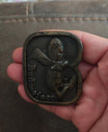 Vintage brass belt buckle with dark patina, Budweiser-themed character front design.