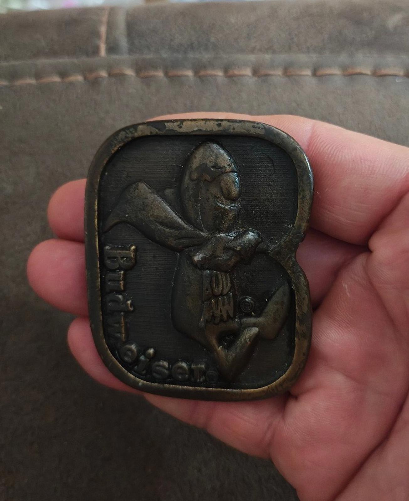 Vintage brass belt buckle with dark patina, Budweiser-themed character front design.