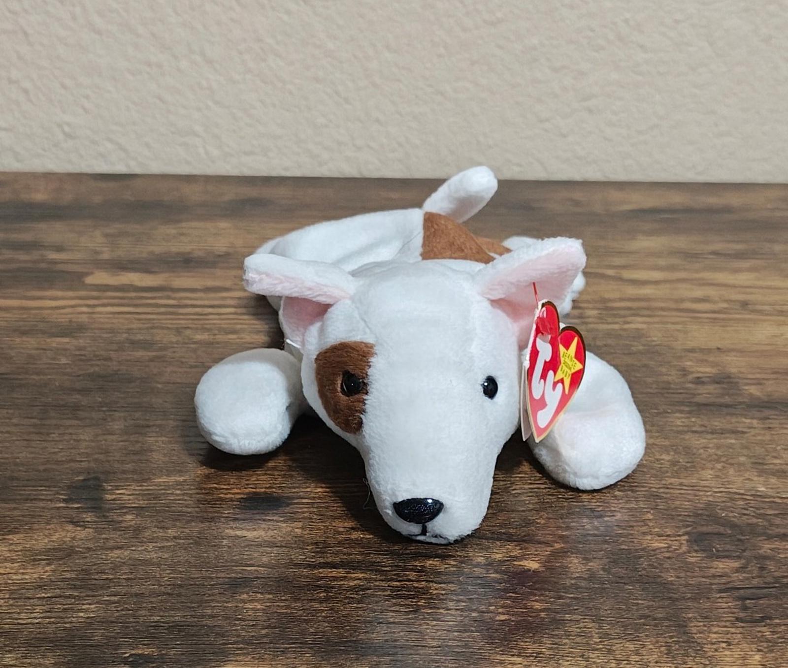 White plush dog lying down with brown ear patch and red Ty heart tag