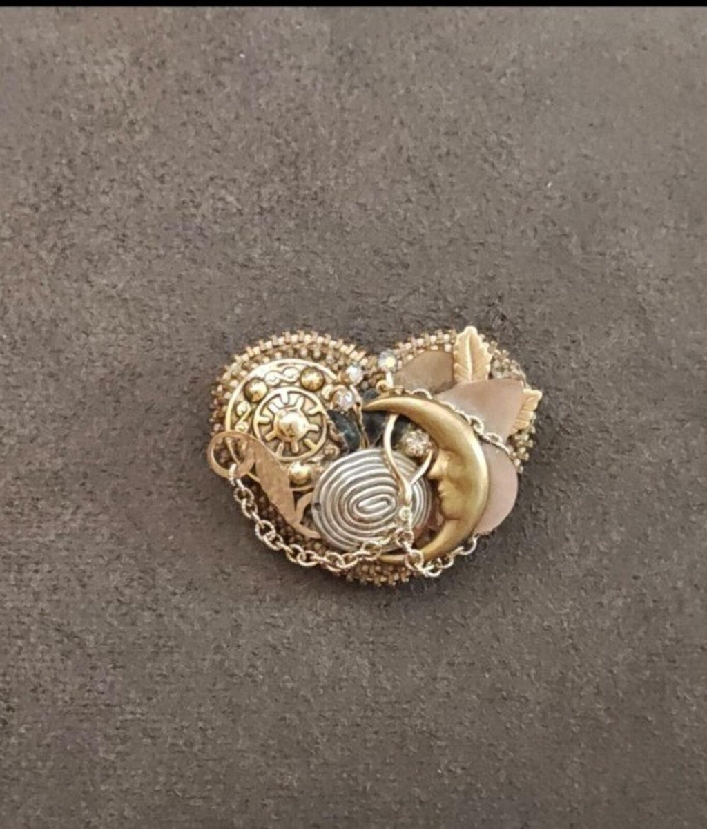 Gold tone celestial charm brooch centered view with moon, sun, spiral, and scalloped charms.