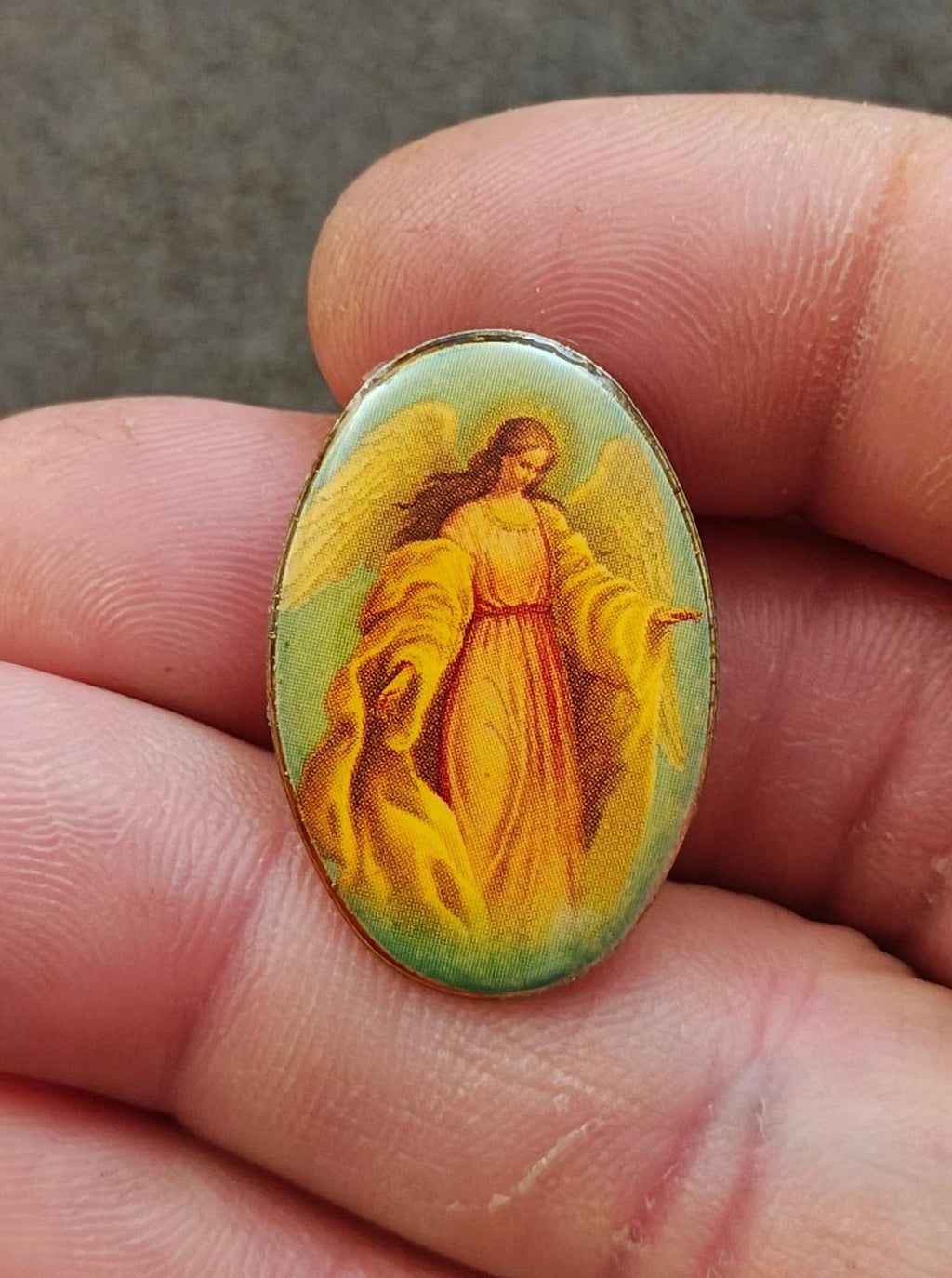 Oval lucite-style guardian angel pin with gold-tone bezel and colorful figure art