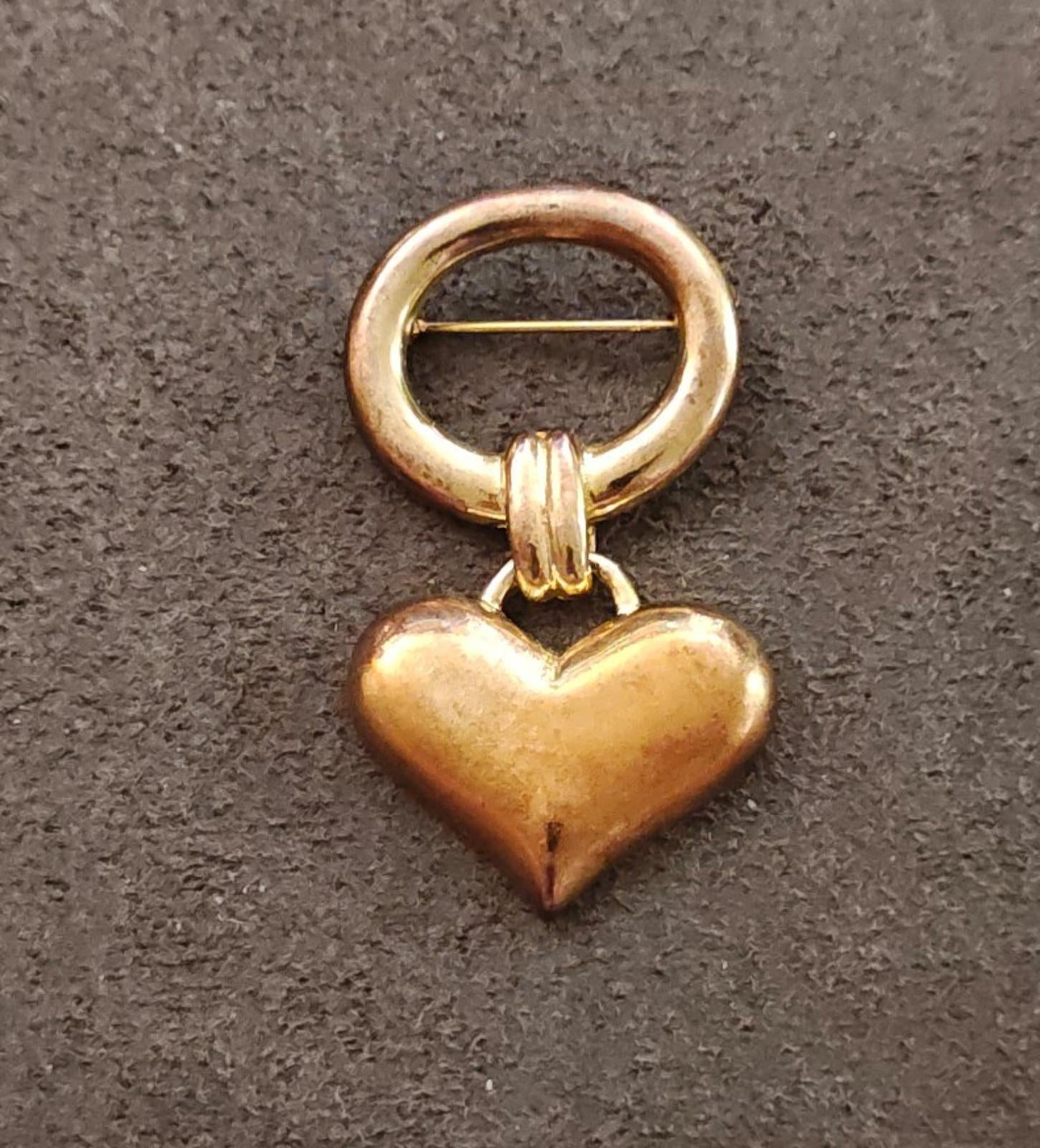 Gold-tone puffy heart charm brooch featuring a circular clasp and hanging heart