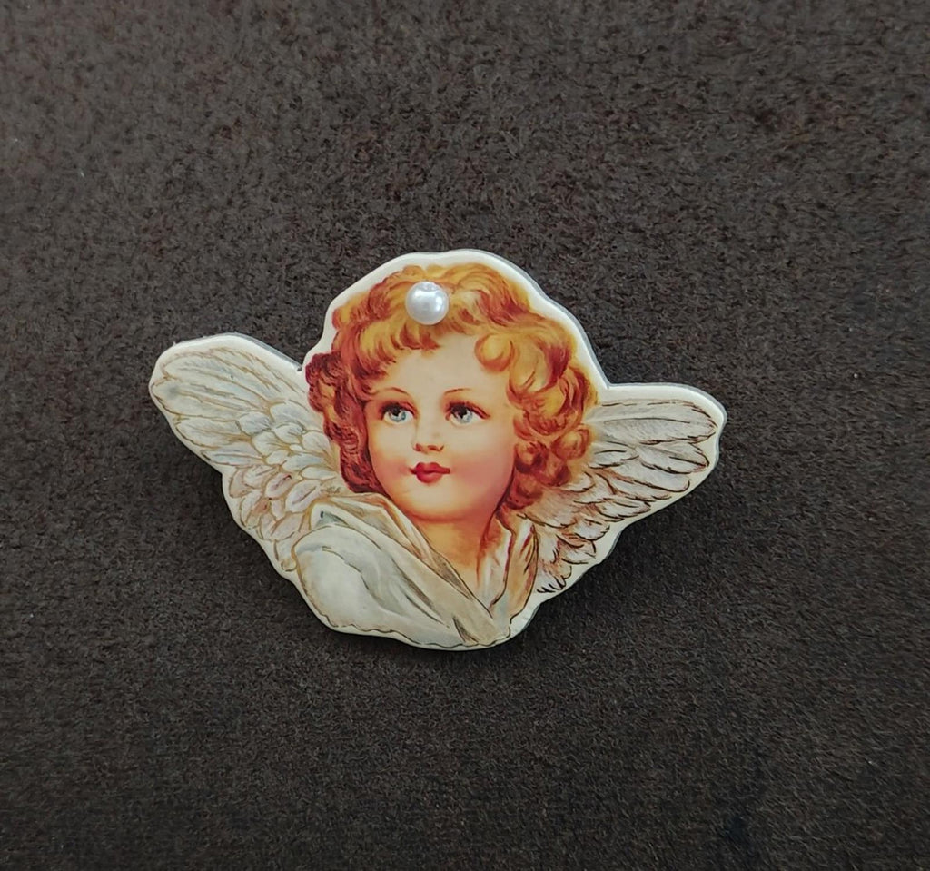 Angel cherub brooch, front view, painted cherub face with pearl detail and pale wings