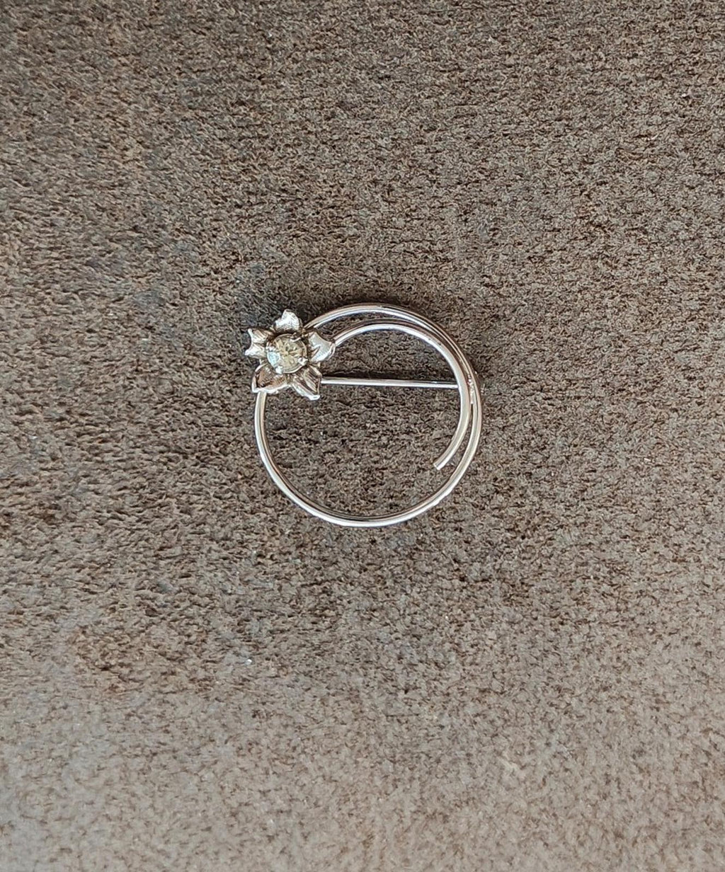 Silver circle brooch with flower applique and faceted rhinestone center