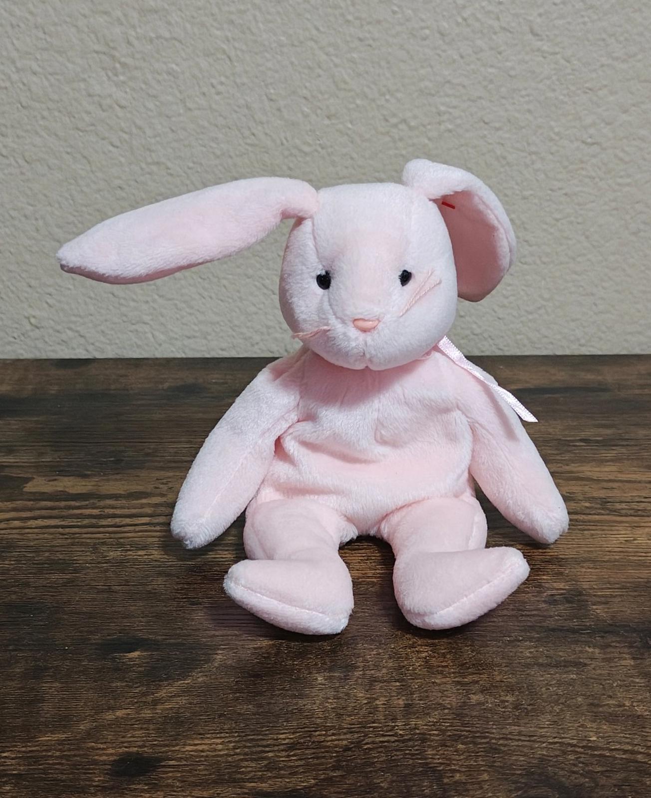 Pink plush bunny beanbag sitting upright with long ears and bow detail