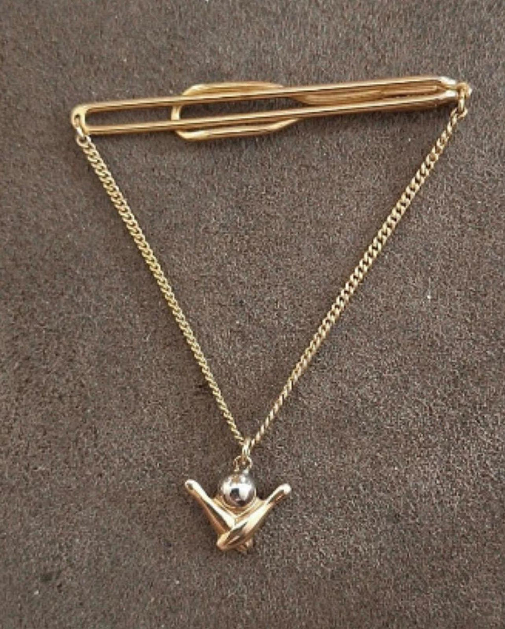 Gold-tone bowling-themed tie bar with chain and pin-shaped charm pendant.