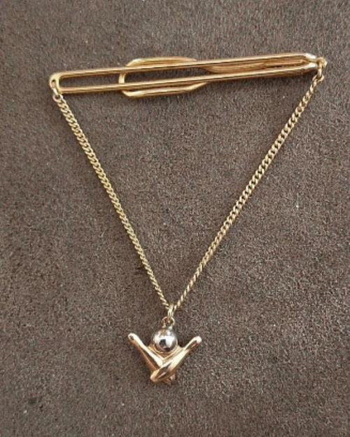 Gold-tone bowling-themed tie bar with chain and pin-shaped charm pendant.