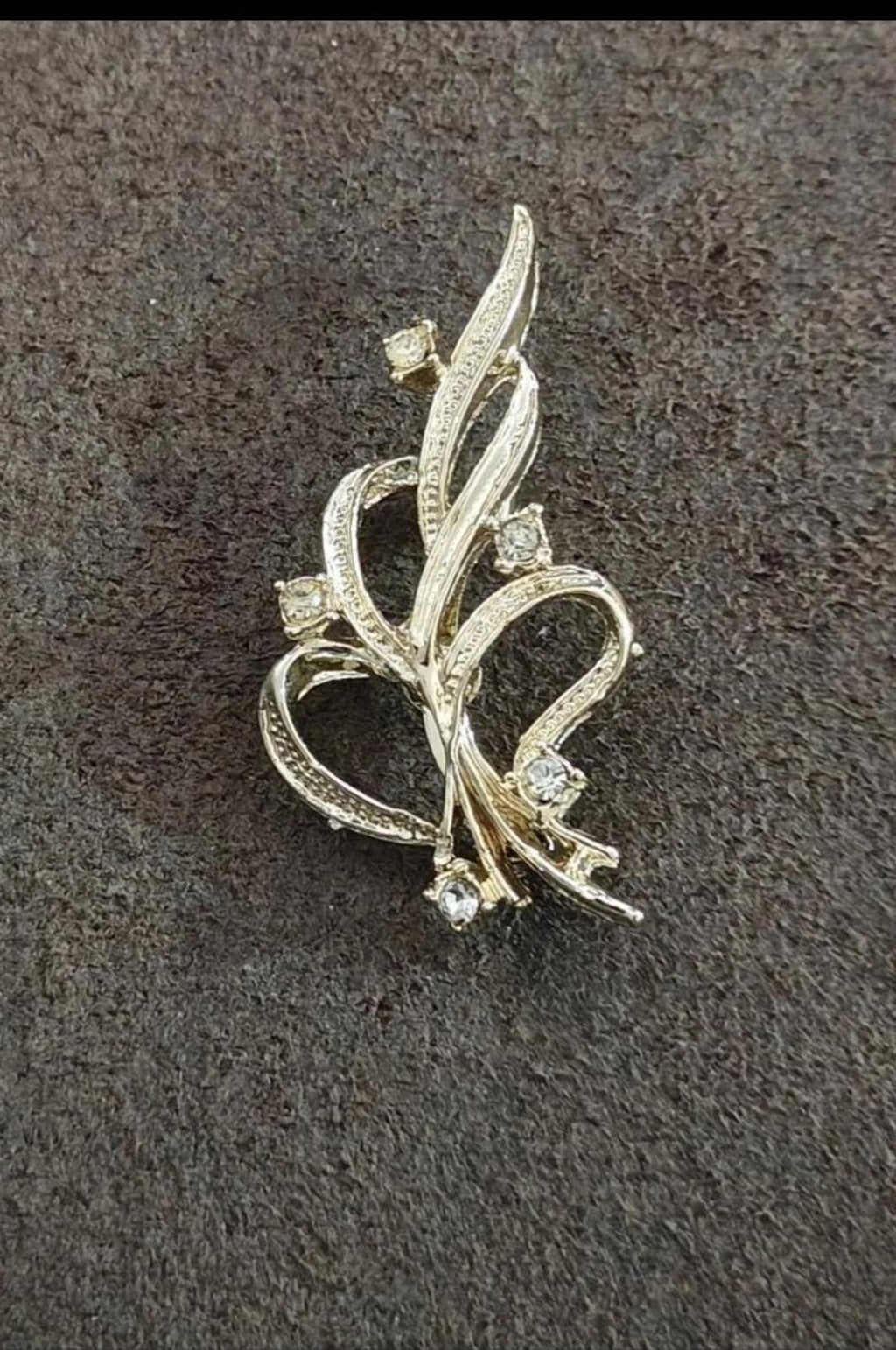 Gold-tone vine ribbon brooch with pointed leaf shapes and rhinestones along the curves