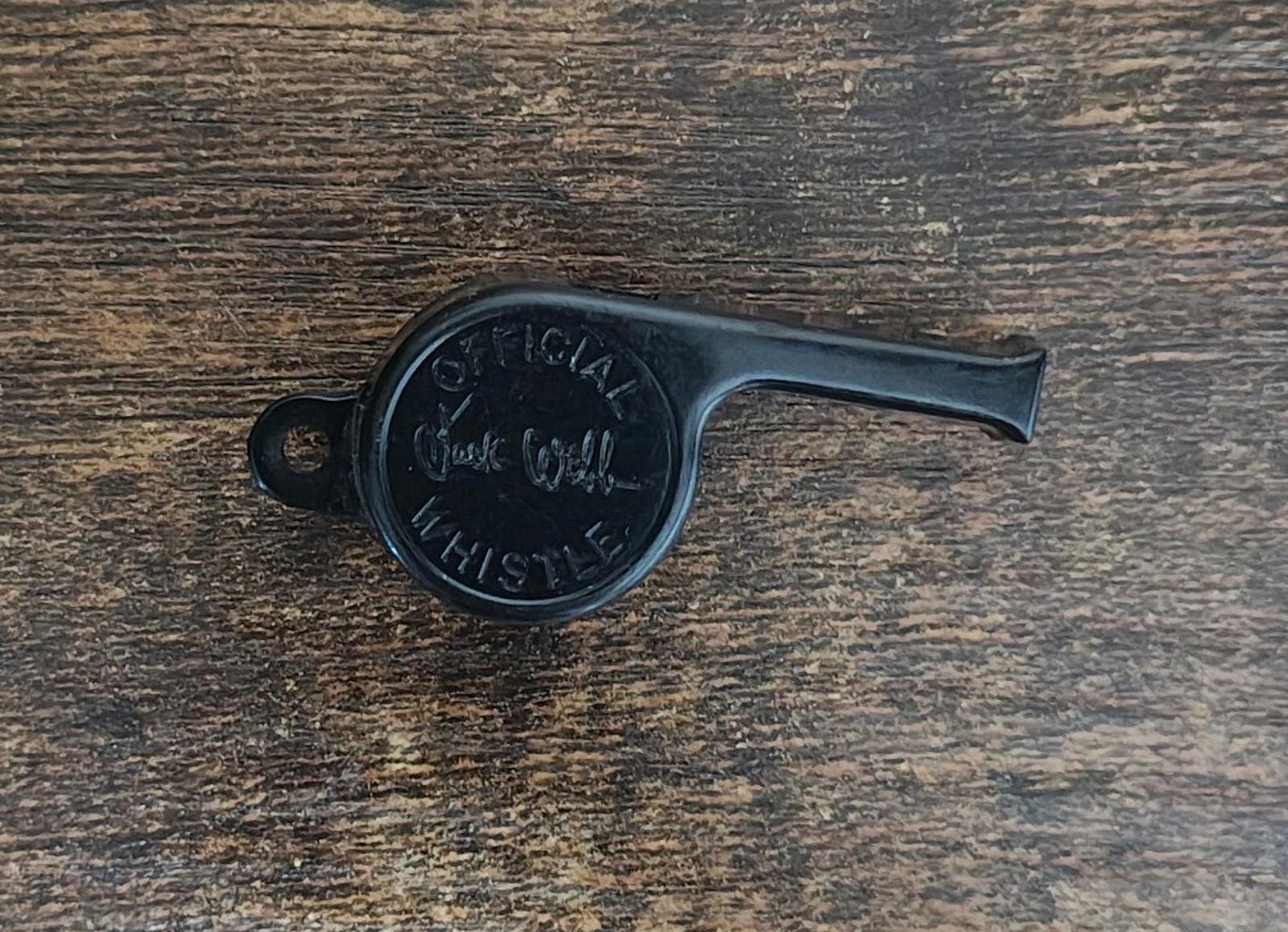 Black whistle back with engraved lettering, laid on a wooden surface.
