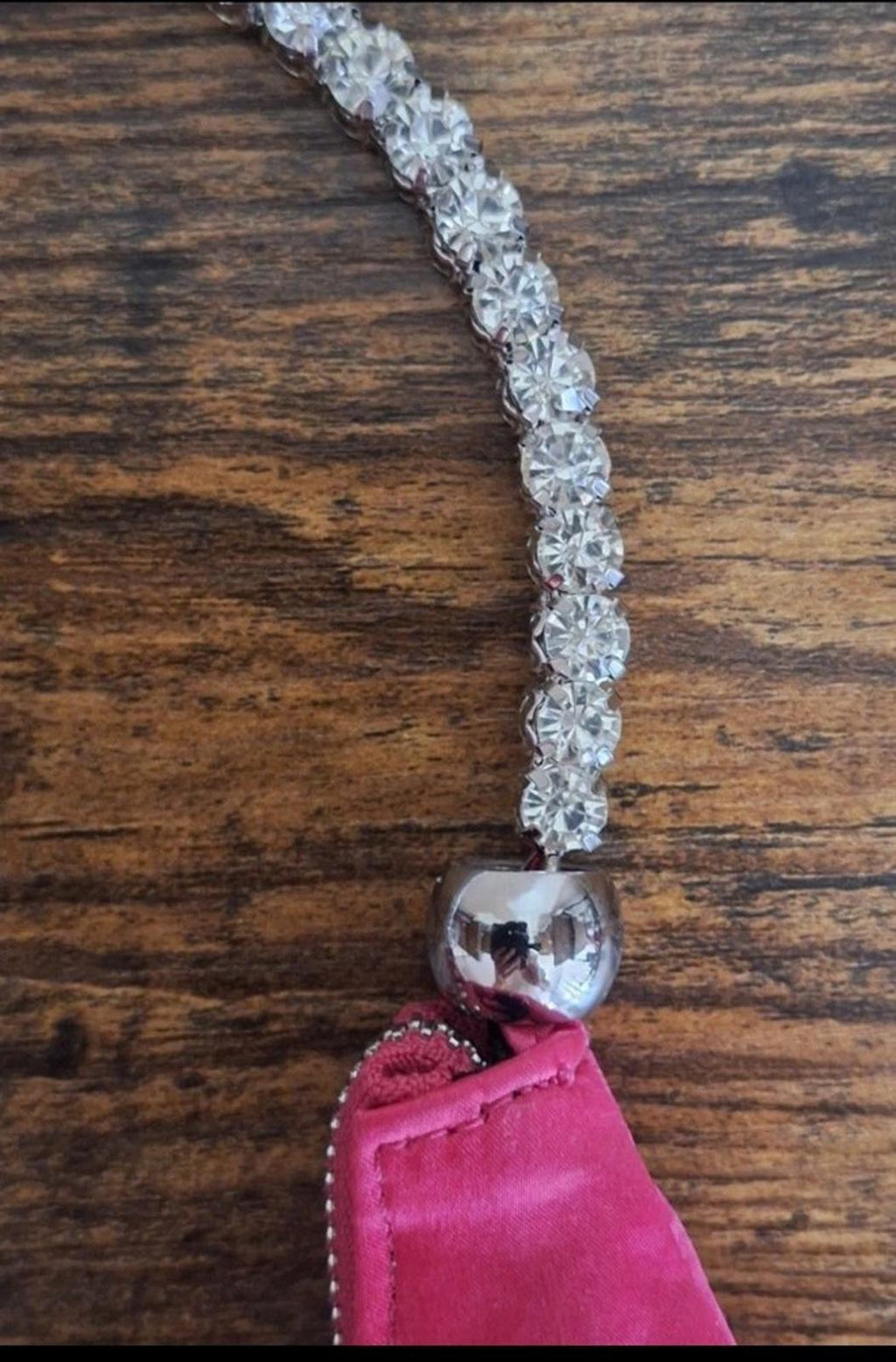 Close-up of rhinestone beaded handle and heart-shaped charm on pink satin bag