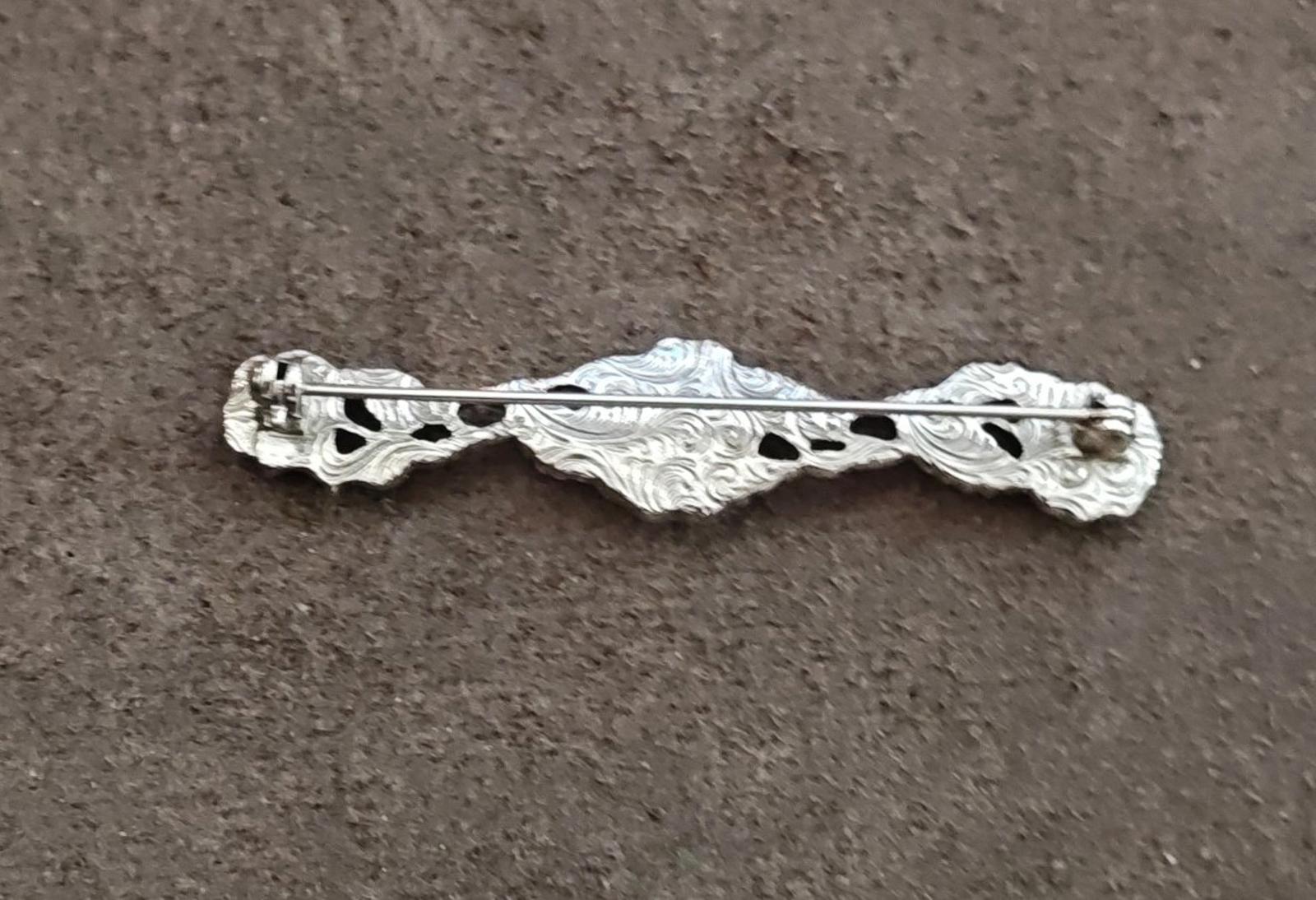 Ornate silver-tone bar brooch back with textured engraving and clasp