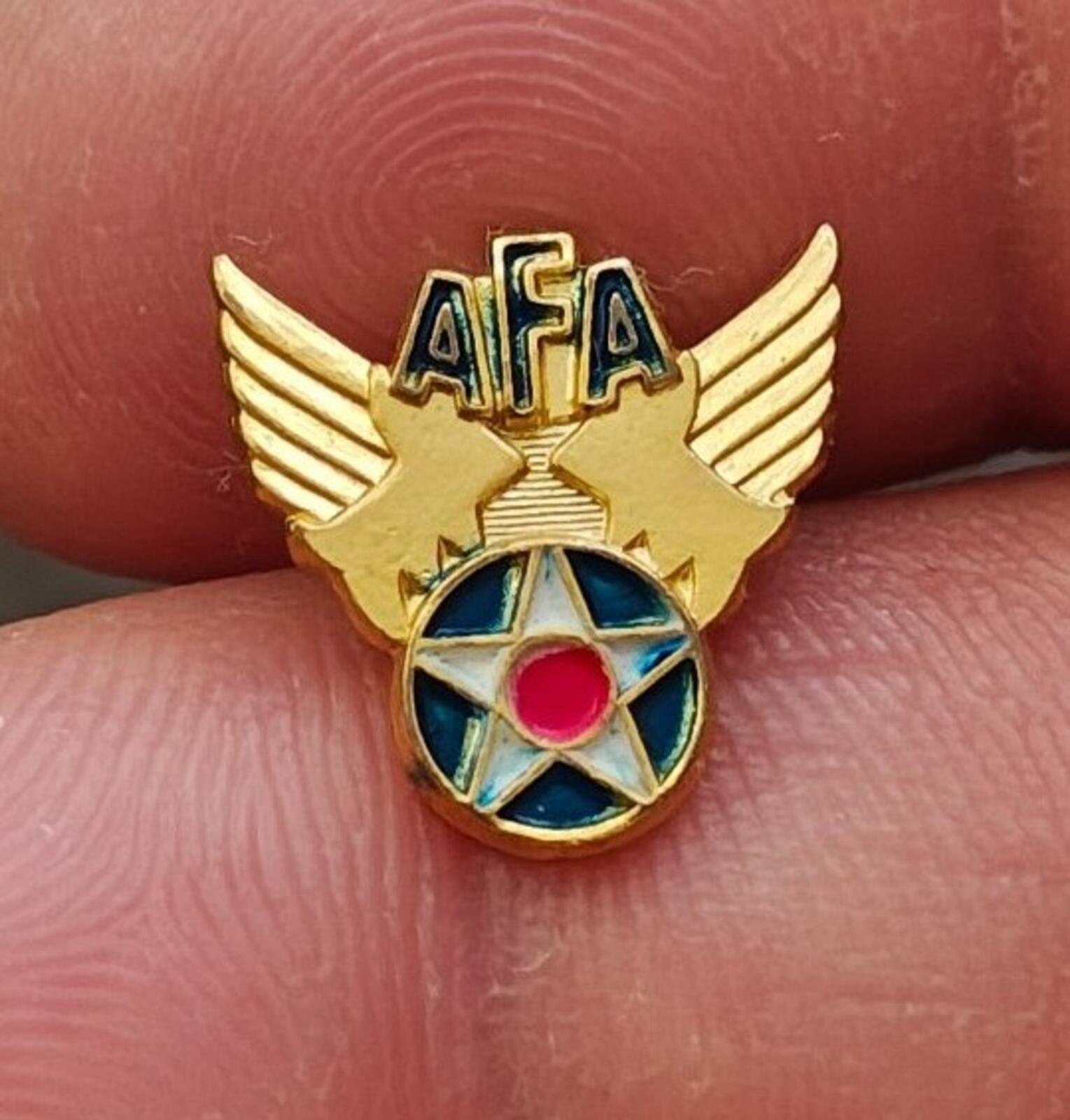 Gold tone AFA winged star enamel pin with blue ring and pink center, front view
