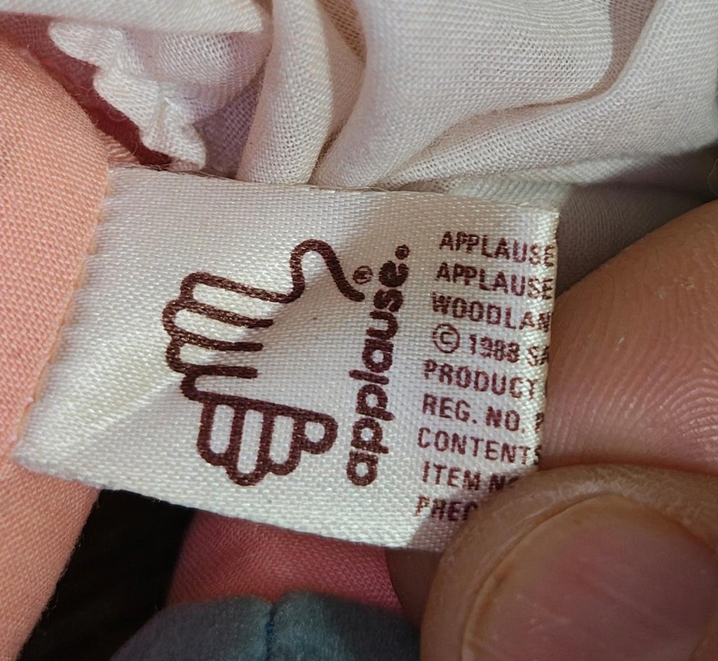 Clothing tag close-up with brown 'Precious Moments' and repeated 'appAlause' text