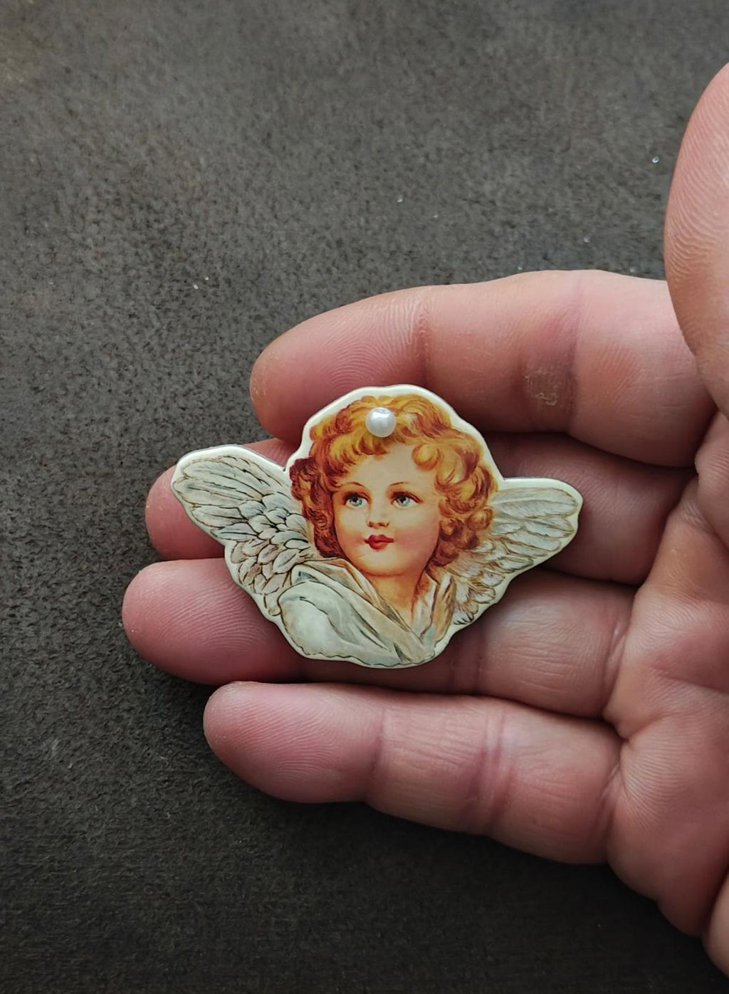 Angel cherub brooch with red-gold curly hair, painted wings, and white pearl center