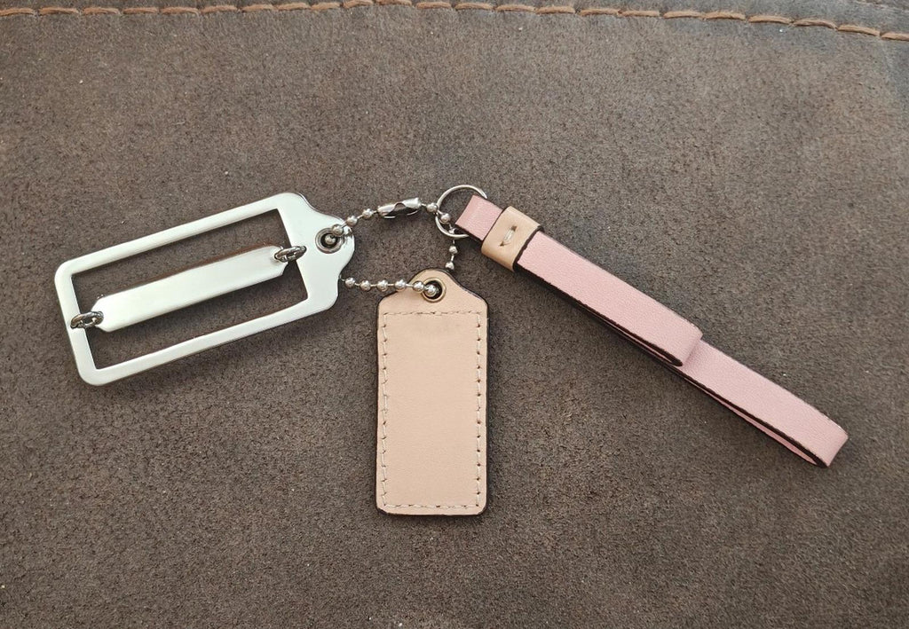Coach bag charm keychain with pink strap, silver hardware, and beige leather tag