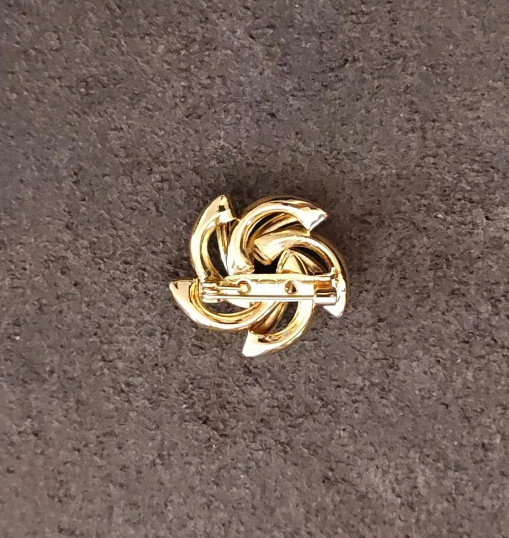 Gold-tone flower brooch with curled loop details, angled view