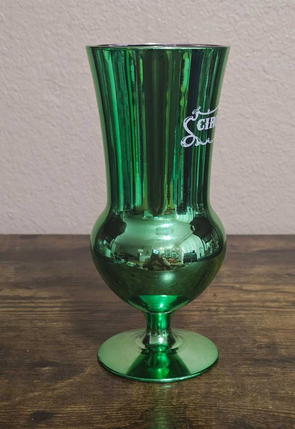 Green mirrored hurricane glass with partial Circus Circus Las Vegas logo on side.