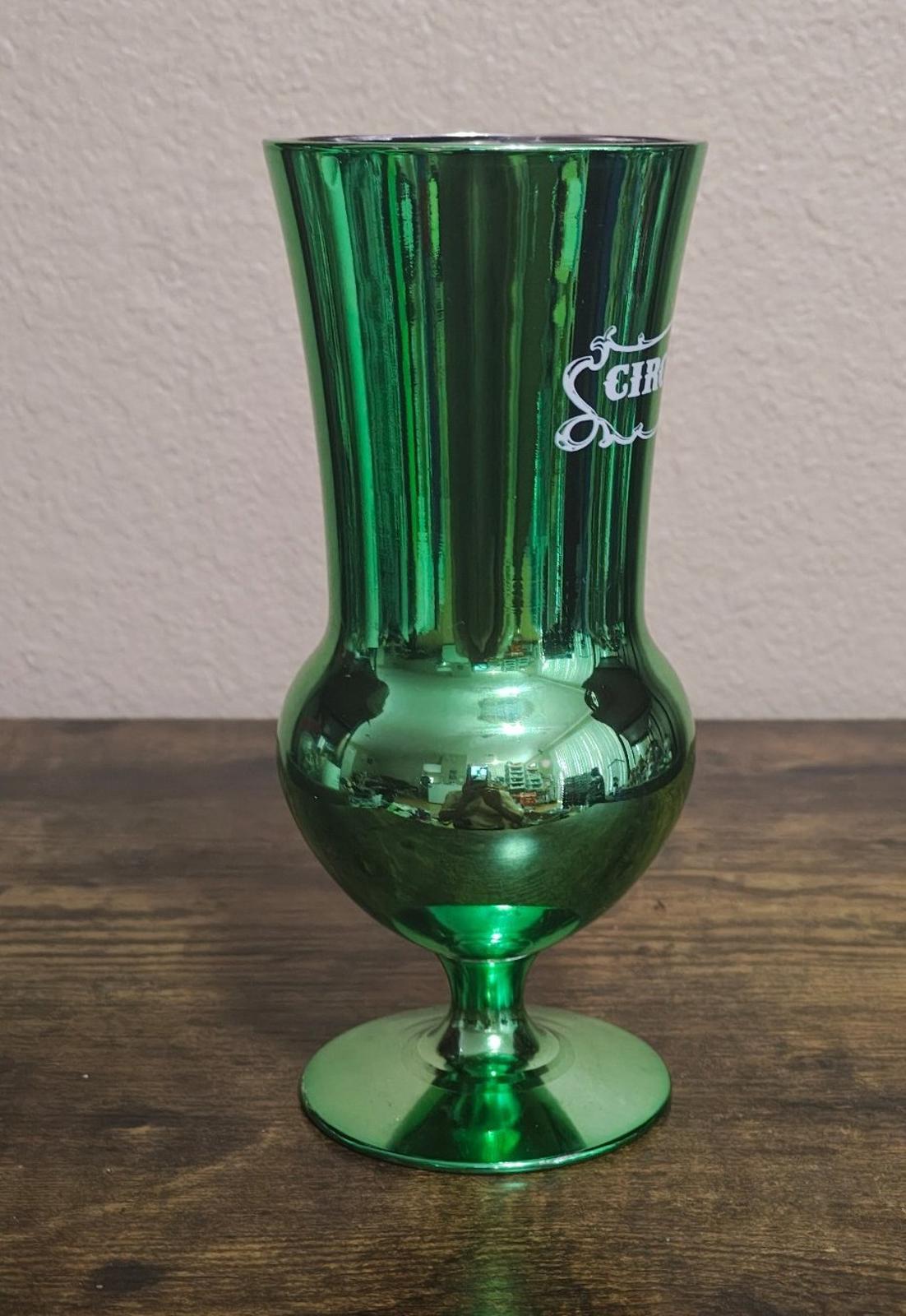 Green mirrored hurricane glass with partial Circus Circus Las Vegas logo on side.