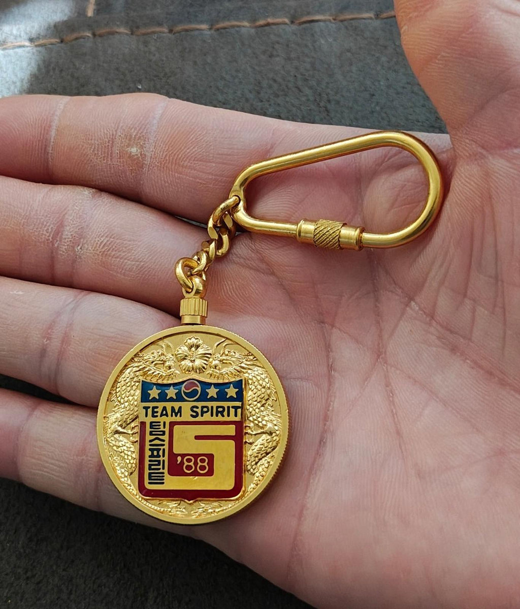 Gold round Team Spirit 1988 keychain medallion with curb-link chain and clasp ring