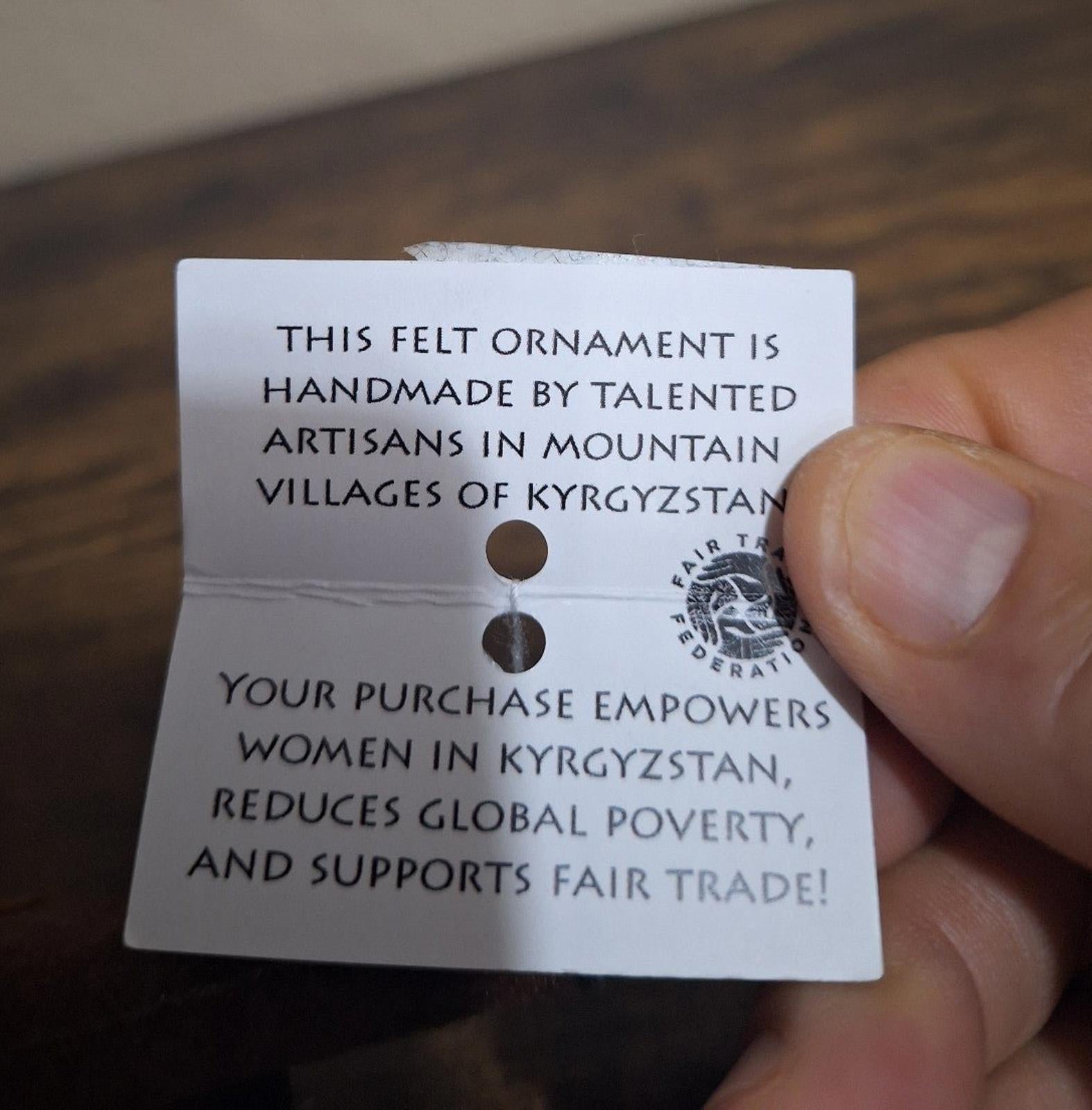 Printed message hang tag attached to felt ornament, white card with dark blue text