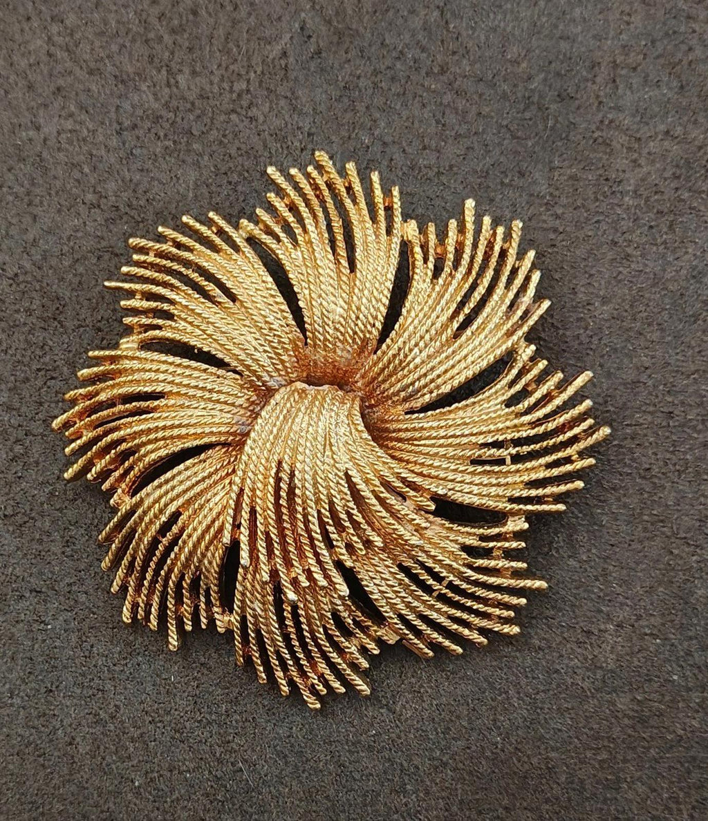 Gold-tone starburst rope brooch, sculpted spiral rays around a central knot