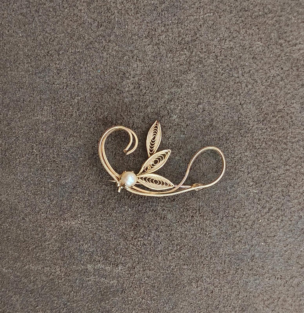 Gold tone leaf filigree brooch with faux pearl bead, curling vine and layered leaf shapes