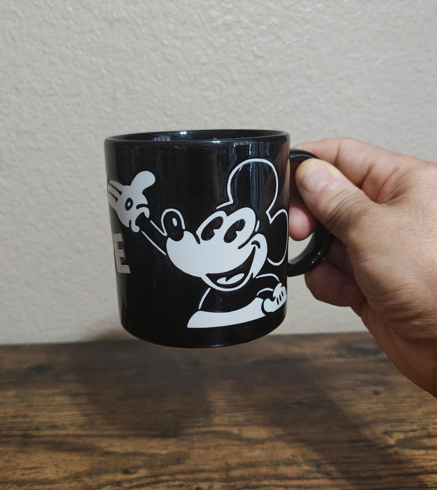Black Mickey Mouse mug with white character holding a small mouse image