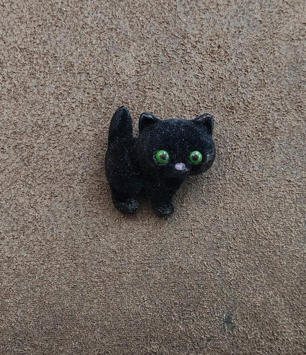 Black fuzzy cat brooch with green eyes