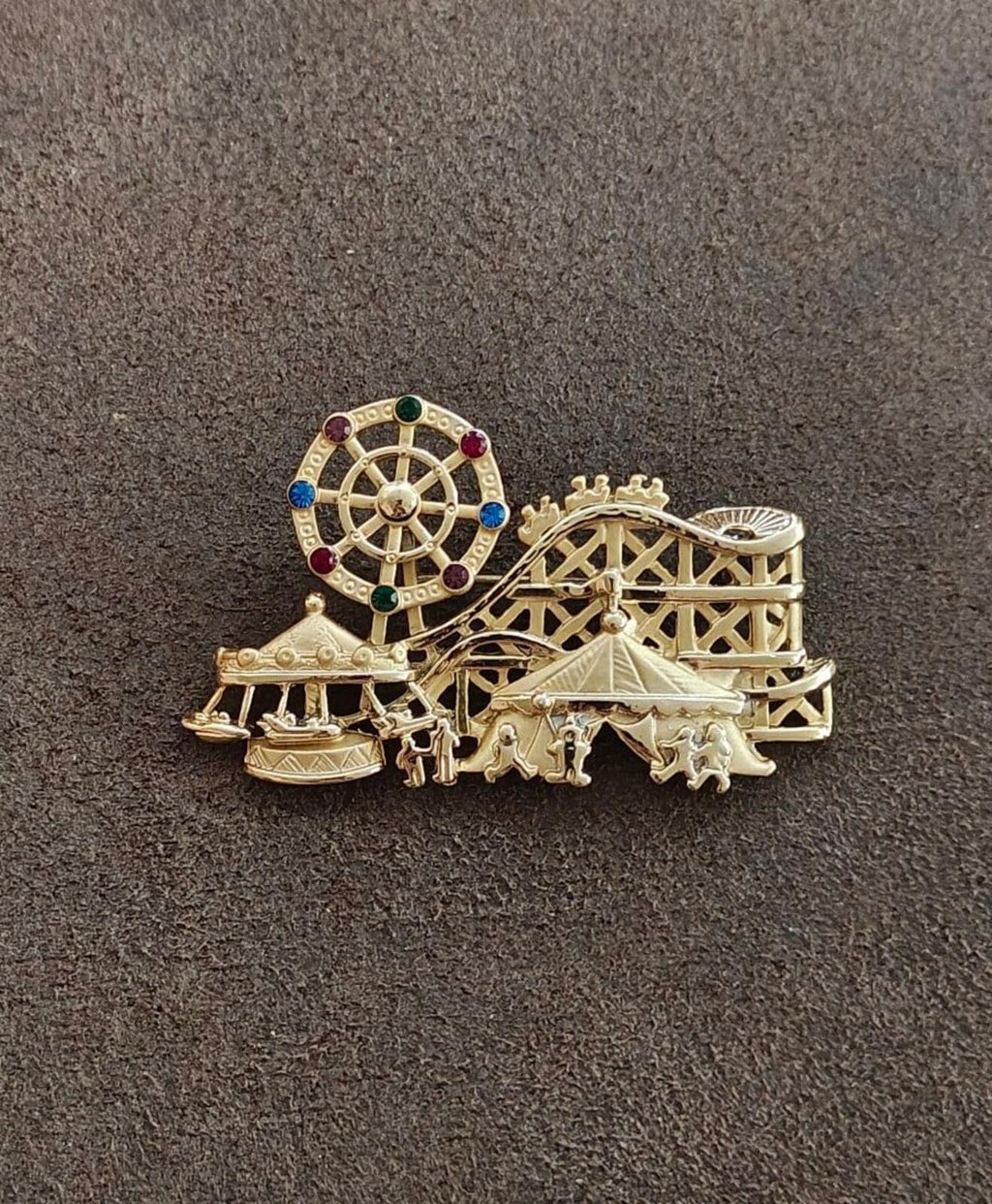 Gold tone carnival themed brooch with roulette wheel, carousel stand, and horses