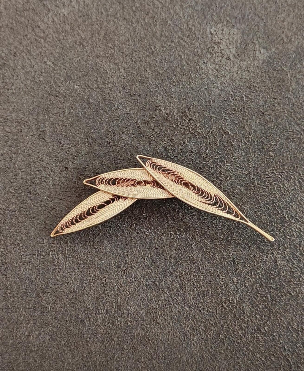 Gold filigree leaf brooch with openwork oval and pointed leaf tips, laid flat