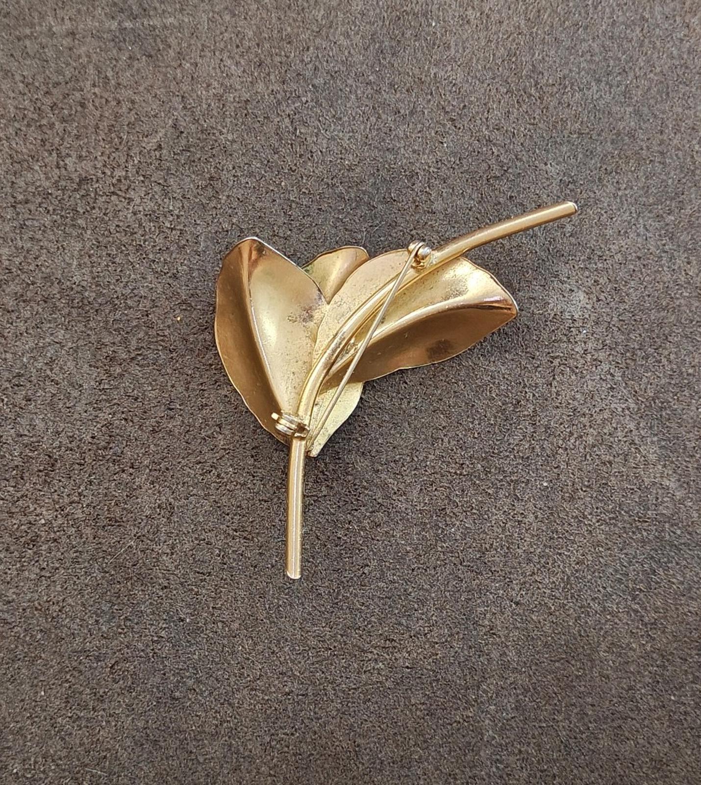Gold tone leaf brooch with textured petals and long pin, viewed from the side